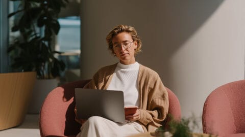 Marketer on chair using laptop and mobile phone