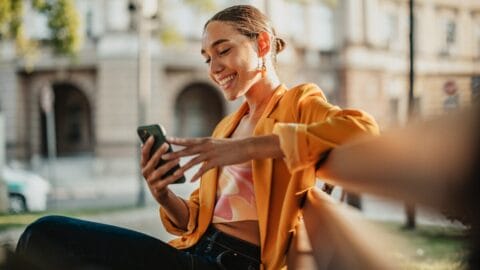 Consumer sitting on a bench smiling because she has received relevant marketing